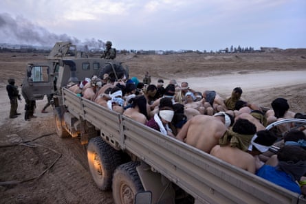 Israeli soldiers stand by a truck packed with bound and blindfolded Palestinian detainees
