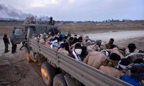 Israeli soldiers guard a vehicle containing bound and blindfolded Palestinian detainees in Gaza.