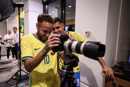 Neymar Jr and Bruno Guimaraes review images on the back of a camera.