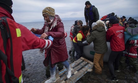 Members of the Greek Red Cross help migrants and refugees to disembark from an inflatable boat in Lesbos.