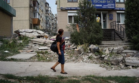 A woman walks past a bombed building in Nikopol
