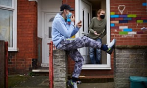 Samy Hassan (sitting) and Gavin Storey (black mask) talking on the doorstep in Gipsyville
