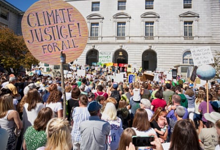A crowd with signs outside on a sunny day.