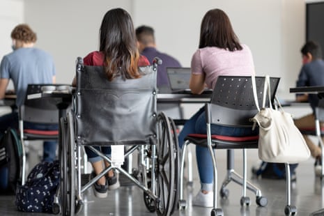 Teen students seen from behind sitting at desks with one sitting in a wheelchair