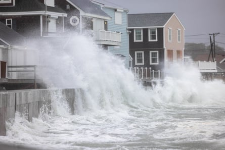 ocean waves splash above seawall and towards houses