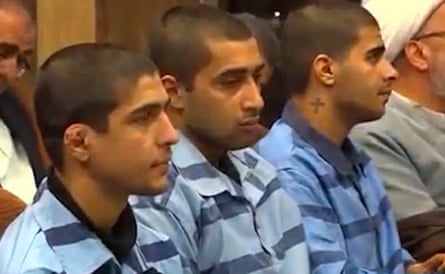Three men wearing striped blue uniforms sit in a row.