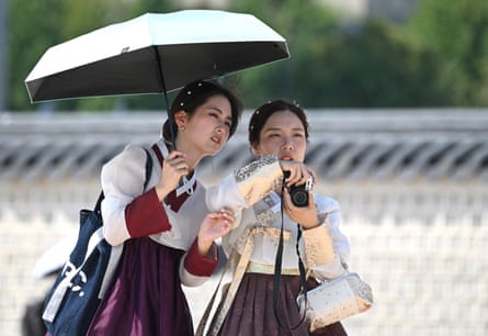 Tourists wearing Hanbok dresses use a parasol at Gyeongbokgung Palace
