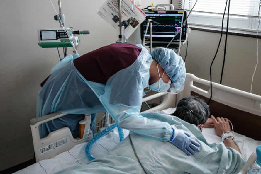 Medical staff wearing personal protective equipment (PPE) speaks to a Covid-19 patient in the prone position at Hokkaido University Hospital in Sapporo on August 3.