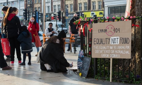A woman writes a note at a public memorial site in Brixton, south London, to draw attention to the increase in domestic and workplace violence against women and non-binary people during the pandemic.