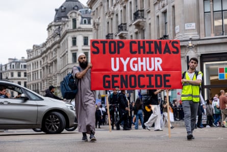 Two men walk through a London street with a sign reading ‘Stop China’s Uyghur Genocide’