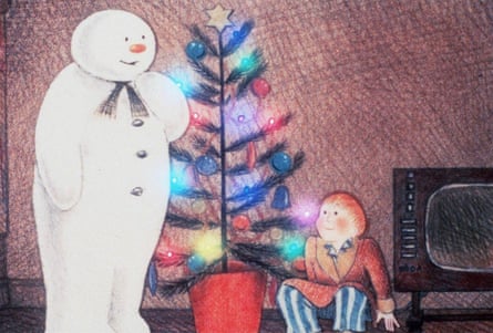 The Snowman stands beside a decorated Christmas tree as a boy crouches nearby watching