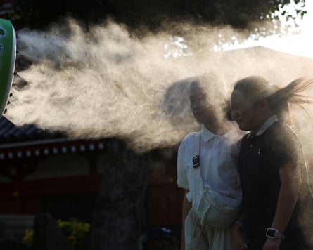Two women standing with their heads in a stream of water vapour