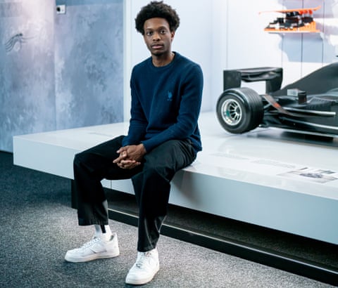 Mission 44 scholar Chris Tagnon sits next to a race car display