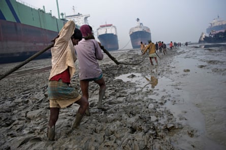 Labourers pull rope on the muddy beach of Chittagong, with huge tankers in the background.