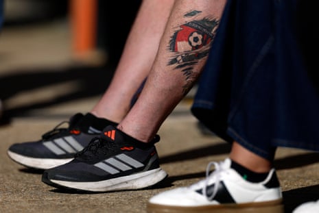 A Bournemouth fan with the club crest tattooed on his calf takes advantage of the sunshine to show off his ink.