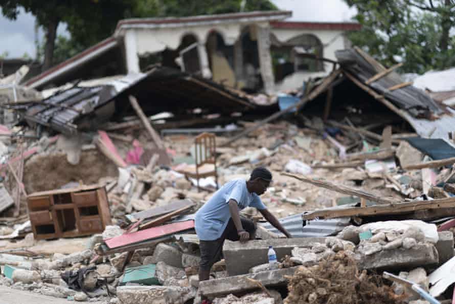 A man searches in the debris of a collapsed house after an earthquake, in Les Cayes, Haiti, on 16 August 2021.
