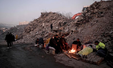 Earthquake survivors huddle around a fire in Kahramanmaraş, Turkey