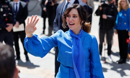 Isabel Díaz Ayuso in a blue dress waving her right hand 
