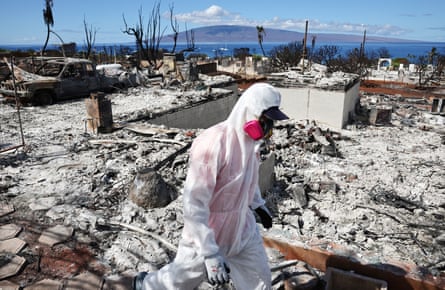 person covered in white and wearing mask walks through rubble