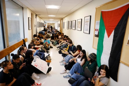 students seated in hallway with palestinian flag