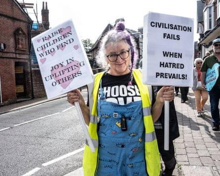 A woman holds signs reading ‘Raise children who find joy in uplifting others’ and ‘civilisation fails when hatred prevails’