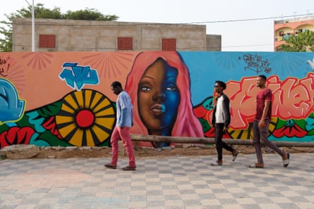 People walk past a graffiti mural in Dakar, Senegal
