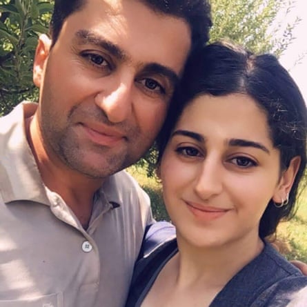 A man and woman hug and smile at the camera