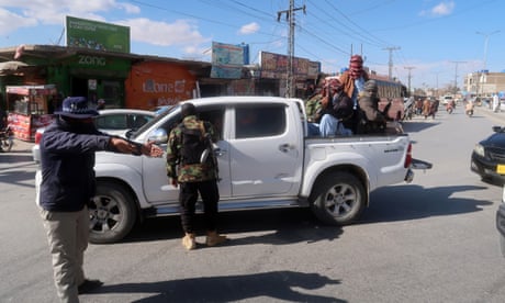 Pakistani security officials stop people in the seats and riding in the back of a white van