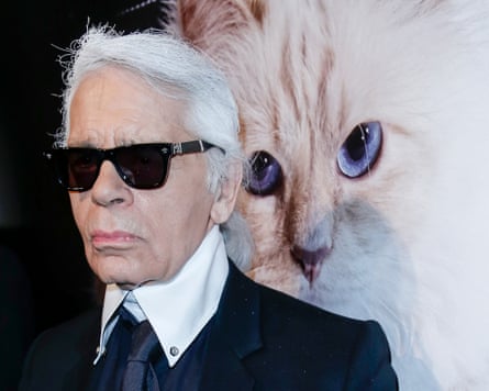 Lagerfeld in dark glasses in front of large image of Choupette's head