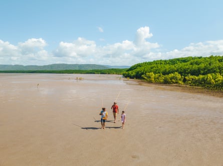 Three people walking on a beach. A Walkabout cultural tour on Cooya beach
