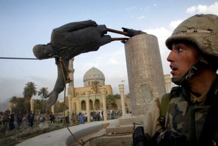 A US soldier with a toppled statue of Saddam Hussein in Baghdad, Iraq, 9 April 2003