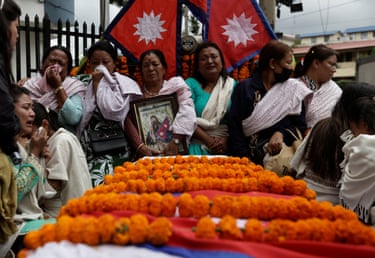 The family of Binod Maharjan surround his coffin, which is covered with orange garlands