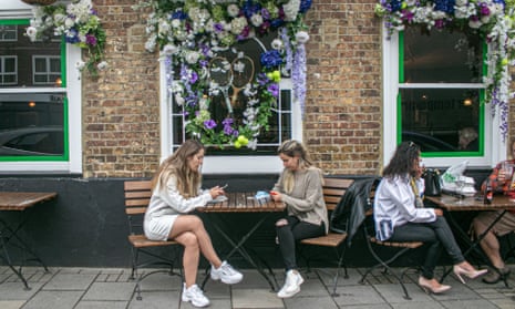 People sit outside a pub in Wimbledon village decorated with a tennis theme for the championships.