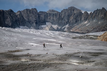 Two mountaineers hiking on the Rhône Glacier, above Gletsch, in the Swiss Alps.