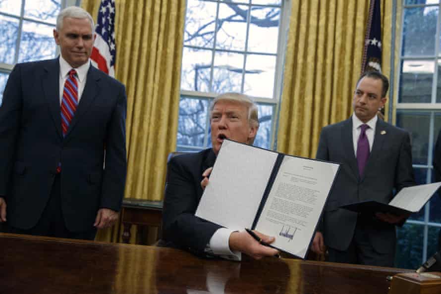 Mike Pence and Reice Priebus look on as Donald Trump shows off an executive order to withdraw the US from the 12-nation Trans-Pacific Partnership trade pact.