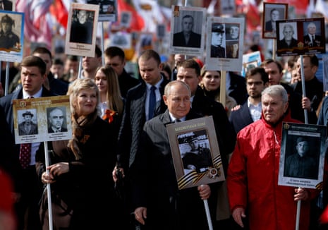 Vladimir Putin holds a portrait of his father in central Moscow, in May 2022.