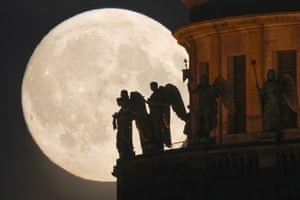 Sculptures of angels fixed at St Isaak’s Cathedral are silhouetted by the full moon in St Petersburg, Russia