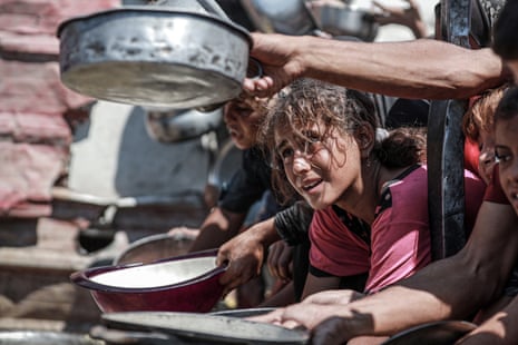 Palestinian children wait with empty pots as a charity distributes food in the Gaza Strip.