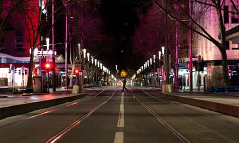 a man crosses an empty city street during Melbourne's nightly curfew