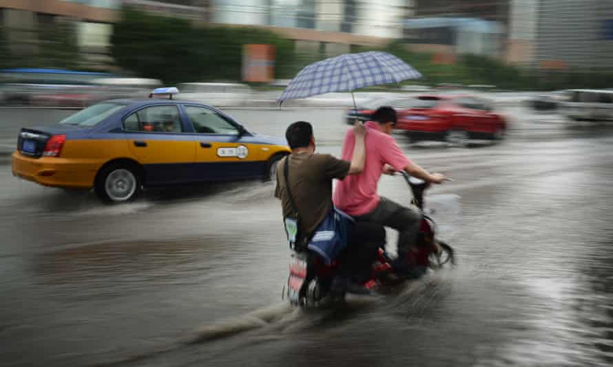 Commuters ride along a flooded road after heavy rains in Beijing on 3 June 2012.