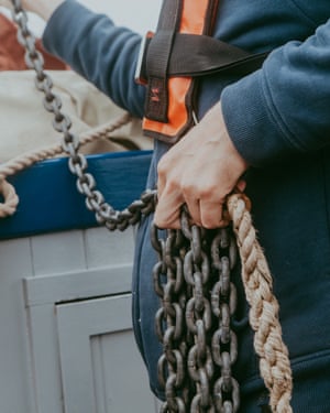 Crew member holding metal and rope cables aboard the Salford whelk boat.