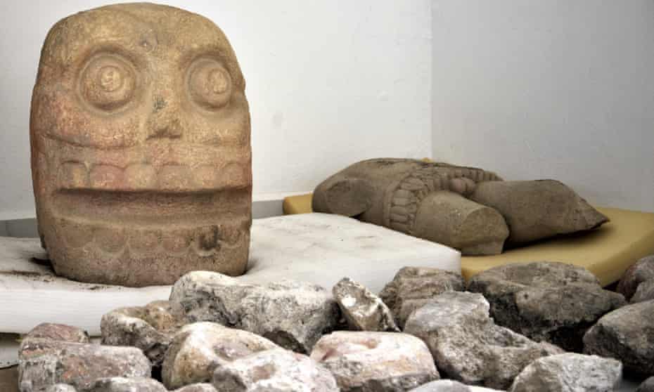A skull-like stone carving and stone trunk depicting the Flayed lord, a pre-Hispanic fertility god depicted as a skinned human corpse. 