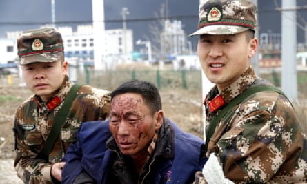 Police help an injured man after the explosion in Yancheng.