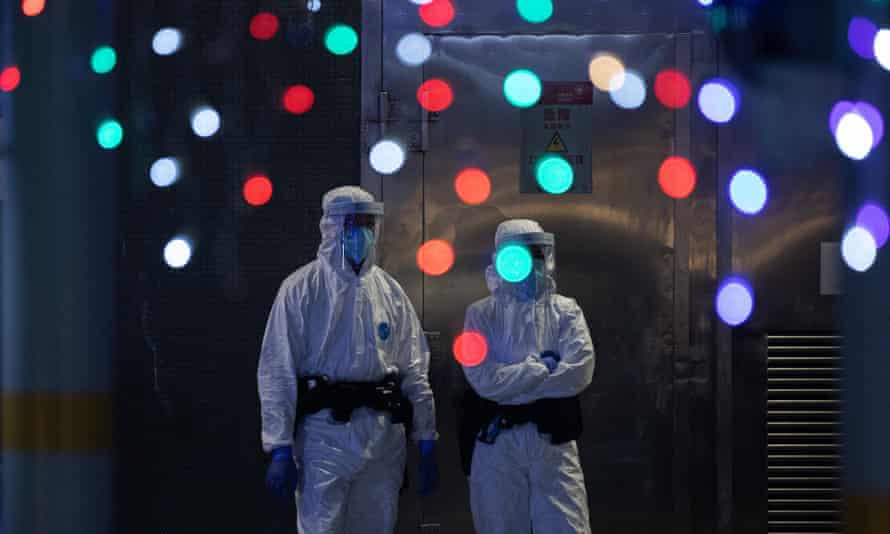 Police officers in protective gear stand guard at the entrance of a public housing building on lockdown in Hong Kong, China, 21 January 2022. The Hong Kong government announced a five-day lockdown of several public housing buildings, home to about 2,700 residents, banning people from leaving their homes, following a Covid-19 outbreak there.