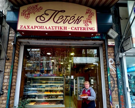 A shop worker standing in the entrance of a shop with a dish.