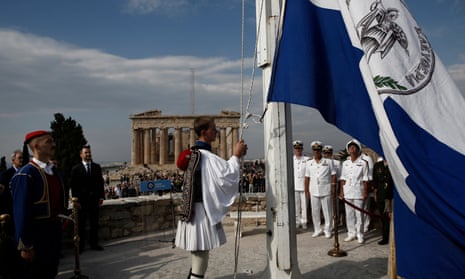 A presidential guard raises the historical Greek flag during a ceremony to mark the 74th anniversary of the liberation of Athens from Nazi occupation
