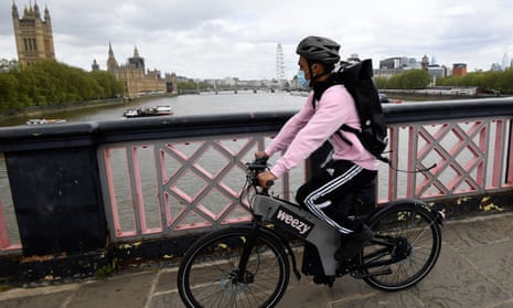 A Weezy courier on a bicycle crosses the Thames in London.