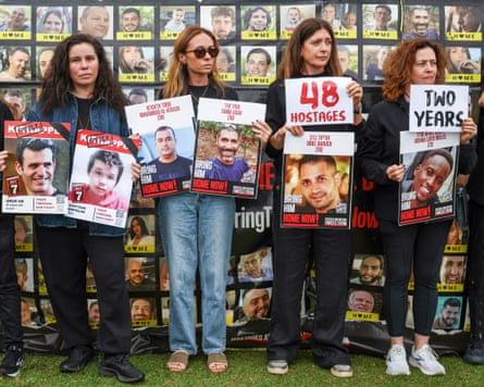 Members of the Australian Jewish community hold a banner and placards bearing the portraits of Israelis held hostage in Gaza