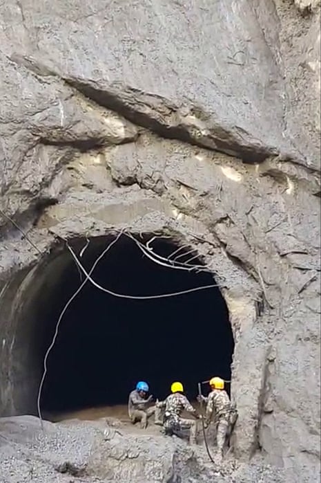 Three rescuers stood outside the tunnel.