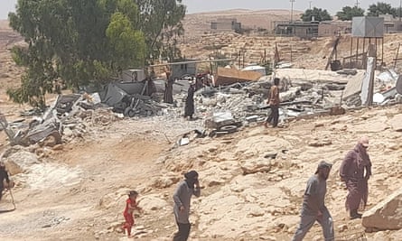 People walk among building debris at Umm al-Kheir.
